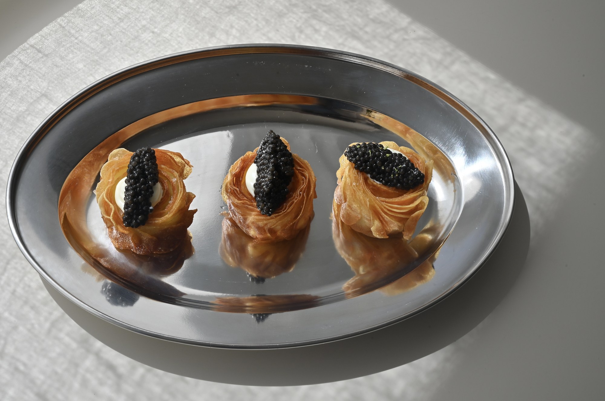 Three potato and caviar bites on silver